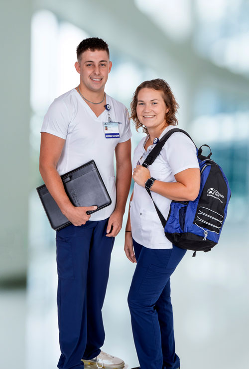 two nurse externs holding a book and backpack